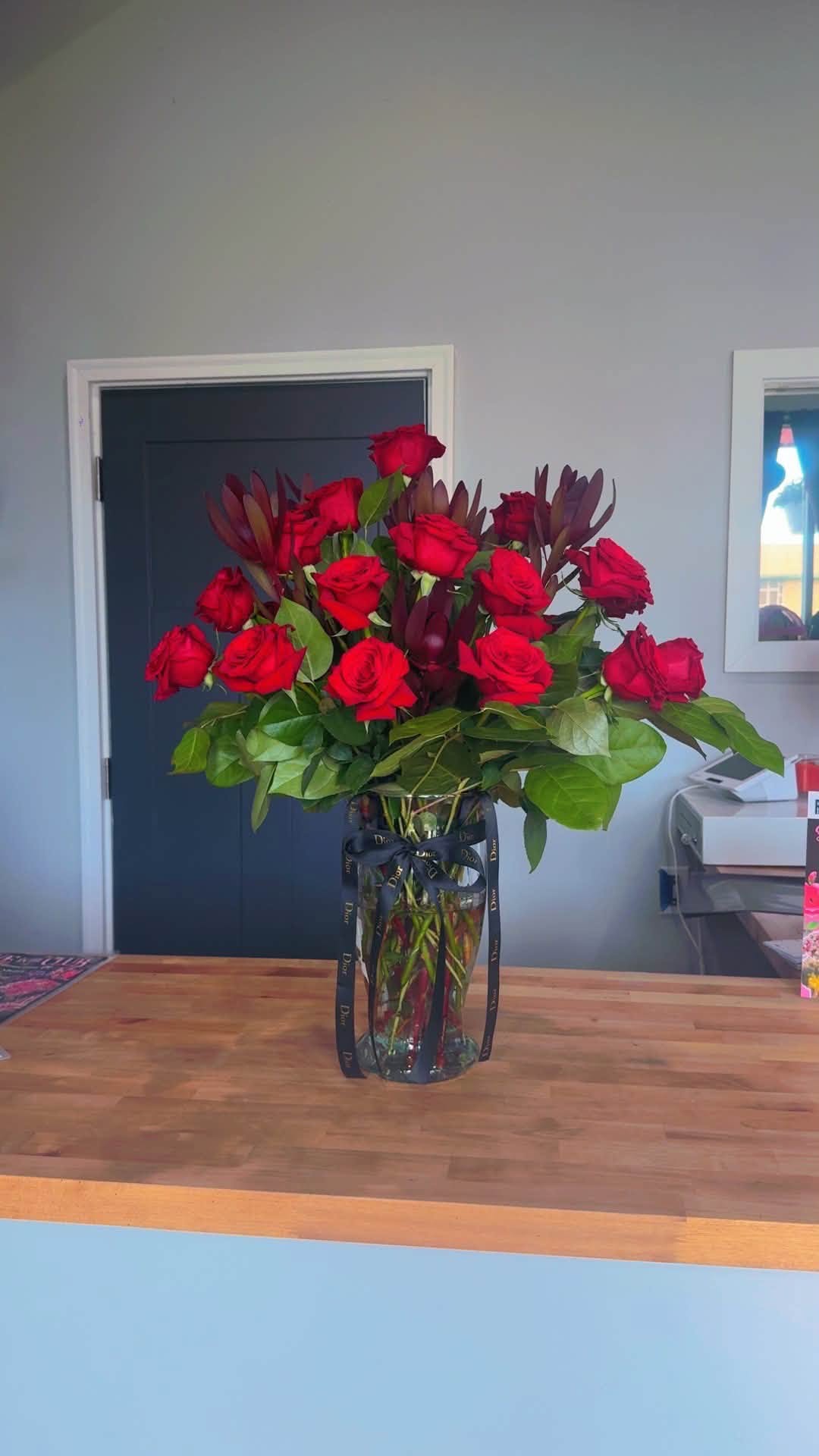 A vase of red roses arranged by Blossoms & Gems