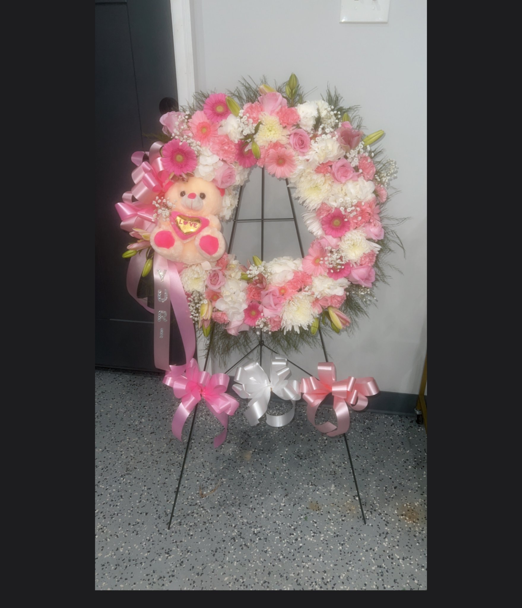 Pink and white sympathy wreath with a teddy bear and pink bows, from Blossoms & Gems